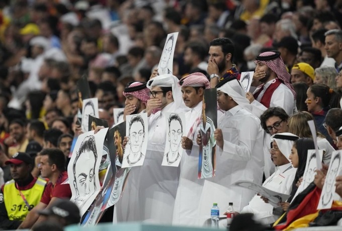 Khán giả Qatar cầm tranh ký họa chân dung của cựu tuyển thủ Đức Mesut Ozil tại Sân vận động Al Bayt ở Al Khor, Qatar, rạng sáng 28/11. Ảnh: AP.